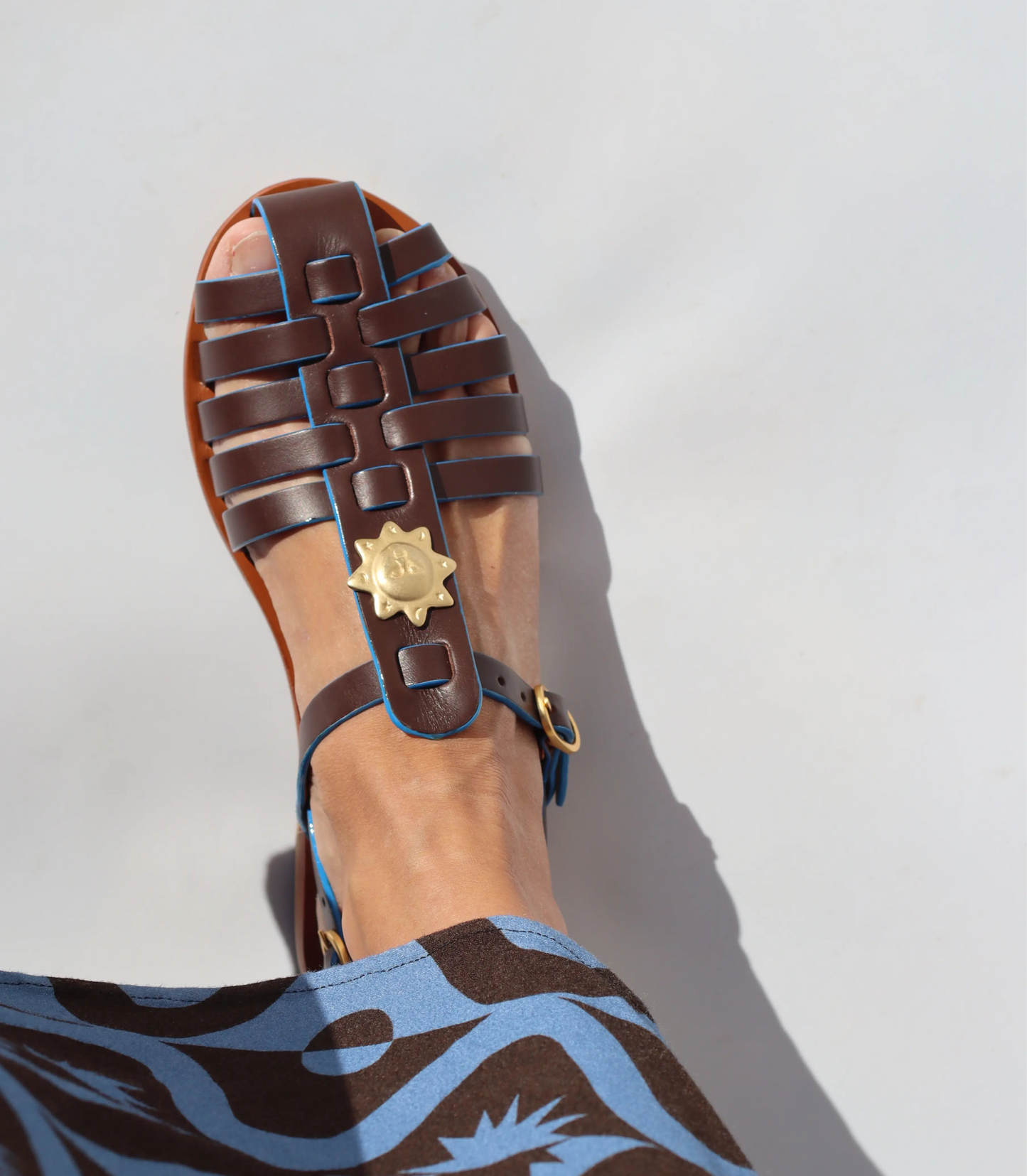 Brown sandal with a decorative buckle on a white background