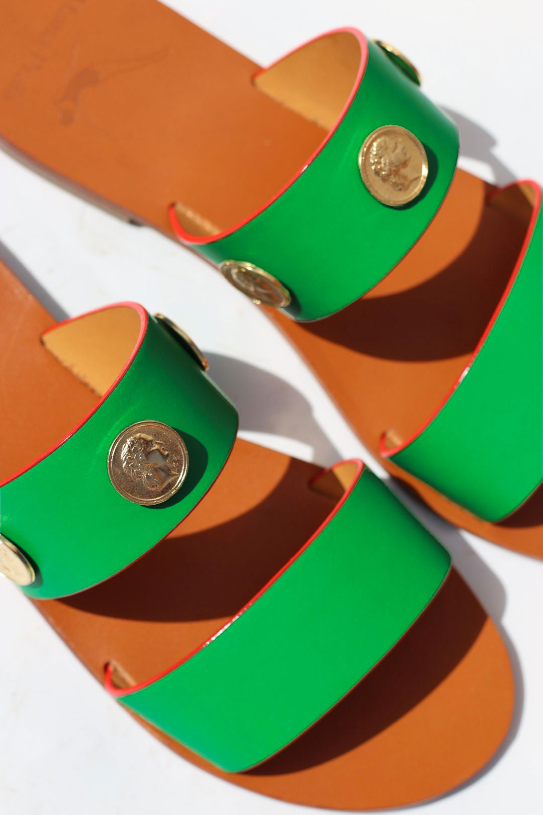 Pair of sandals with green and red striped straps on a white background
