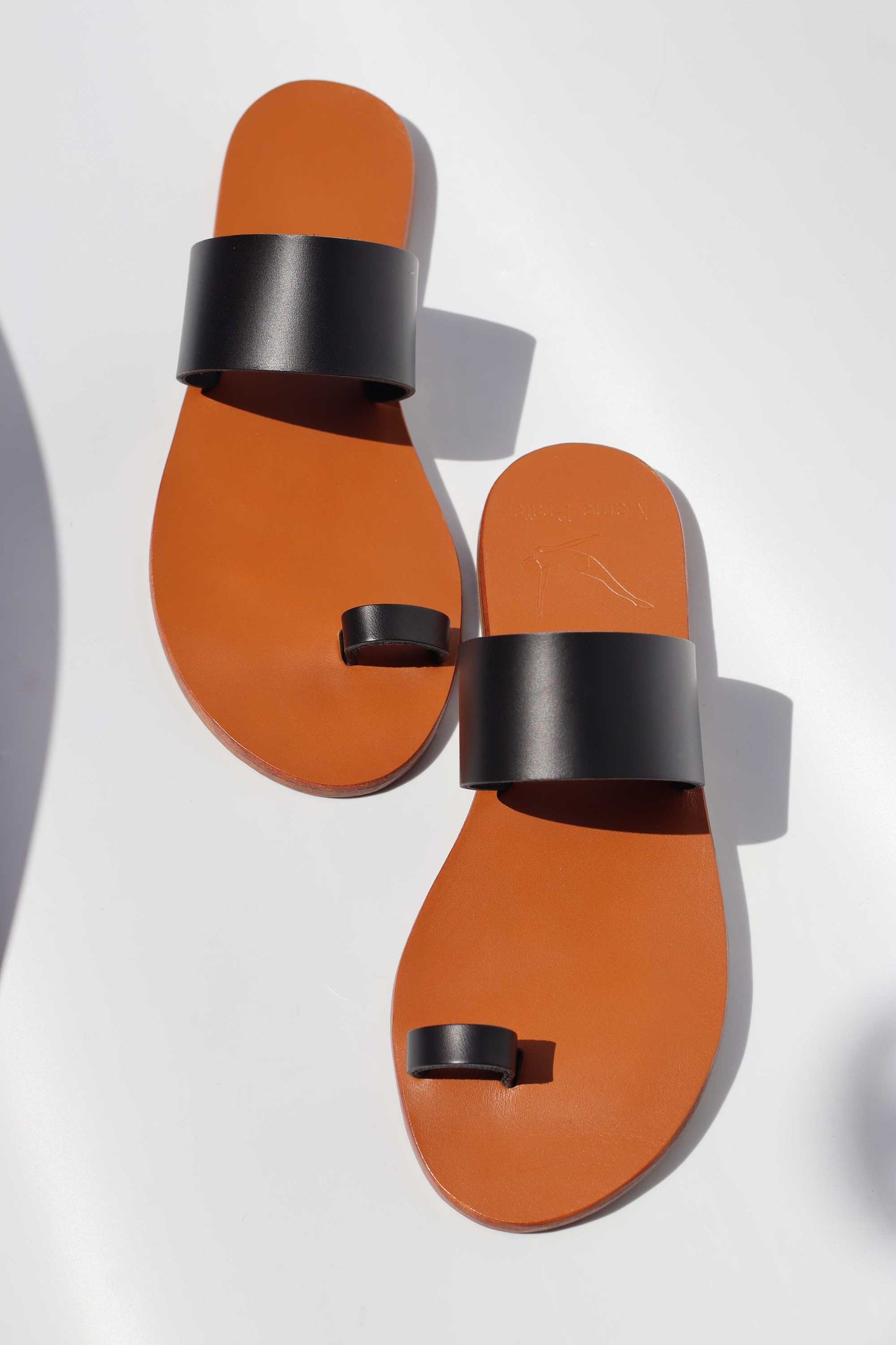 Pair of camel sandals with black straps on a white background