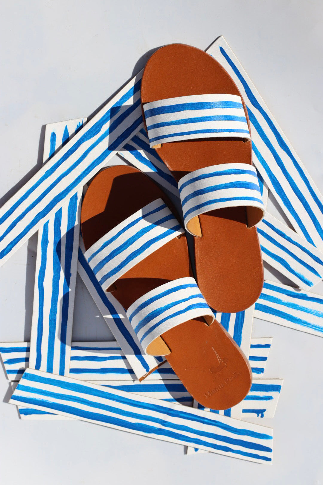 Pair of sandals with blue and white striped straps on a matching striped background