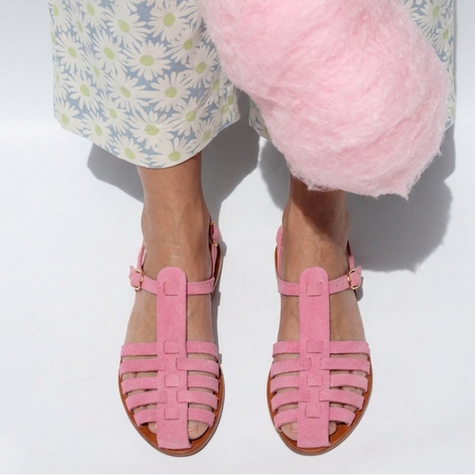Person wearing pink sandals holding pink cotton candy against a white background