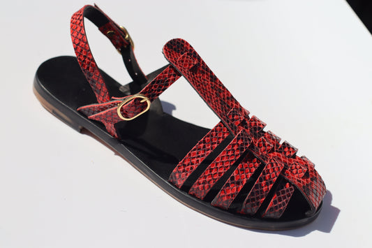 A pair of red and black snake-inspired leather caged toe flat sandals with hand-dyed black soles.