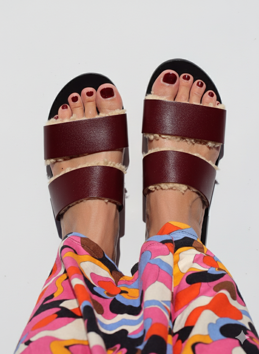 zoom on the foot of a woman wearing multicolor pant and sheepskin sandals
