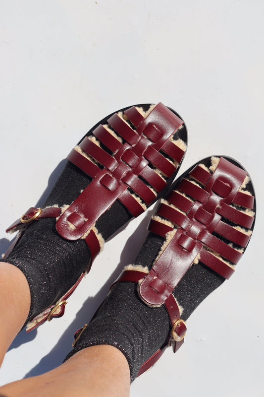 Pair of burgundy woven sandals on a white background