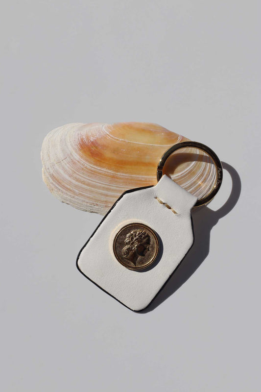 Close-up of keyring on a shell with a magnifying glass on a light gray background