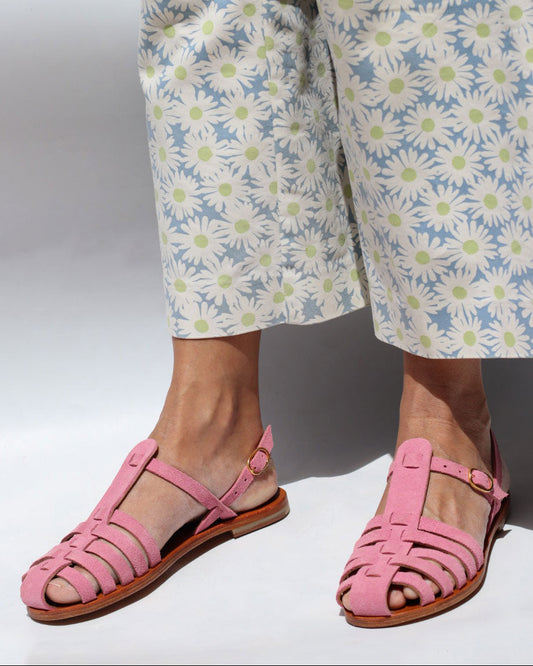 Person wearing pink sandals and floral pants on a white background