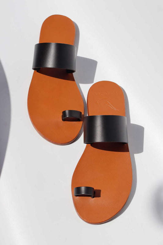 Pair of camel sandals with black straps on a white background